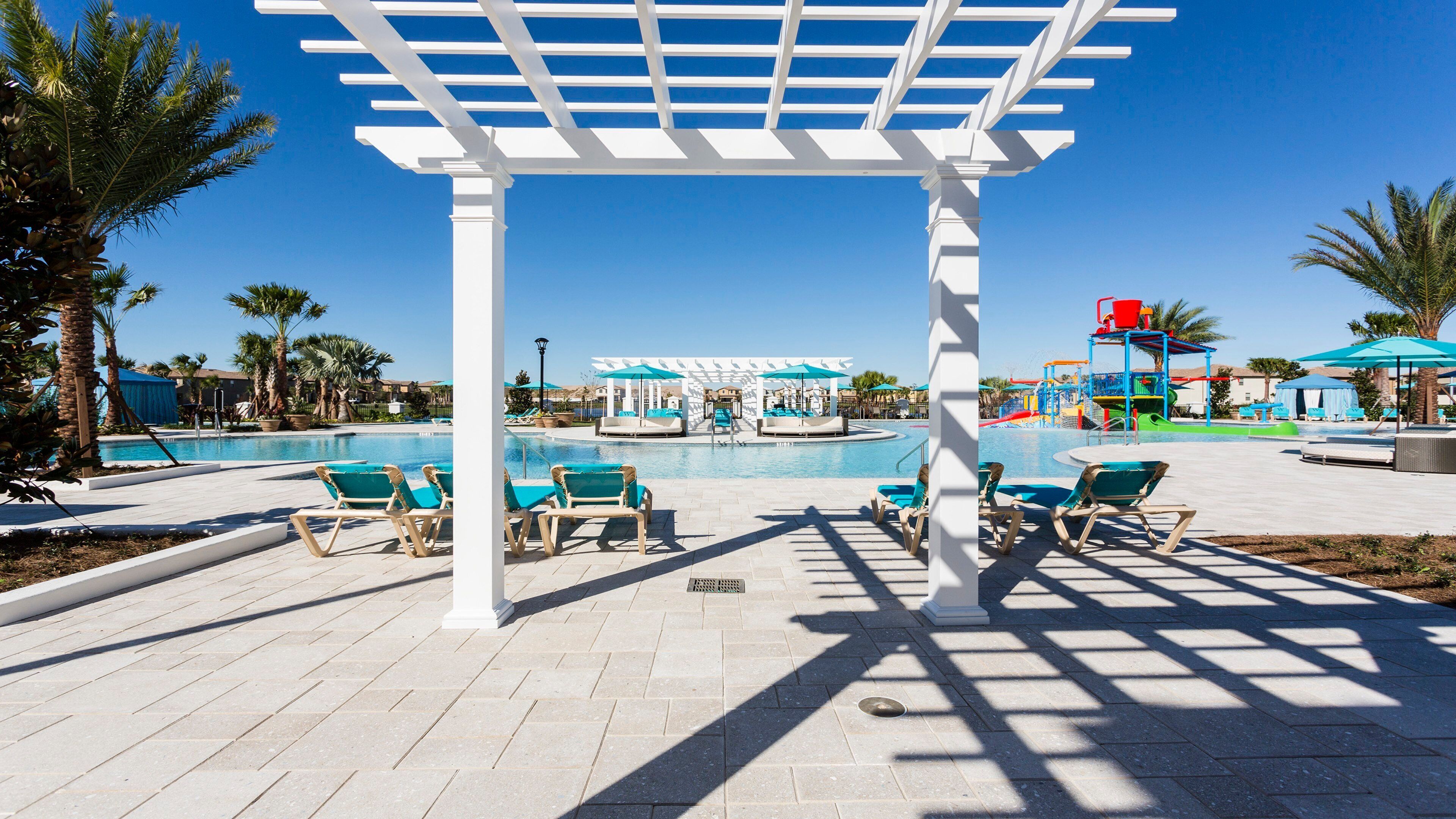 Un área de piscina con sillones de descanso, una pérgola y un parque acuático.