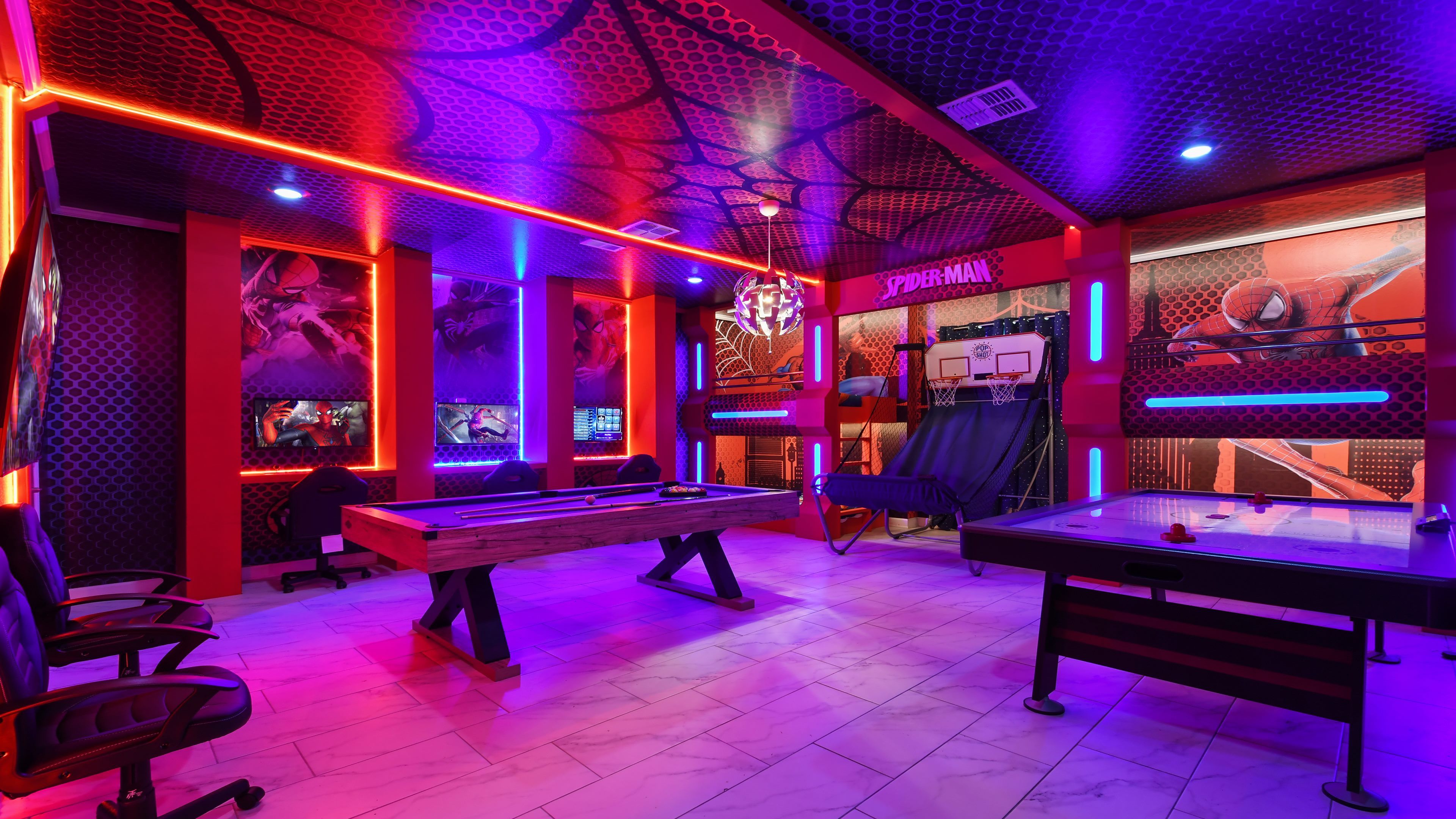 A gaming room with pool tables, a Spiderman-themed wall, and LED lighting.
