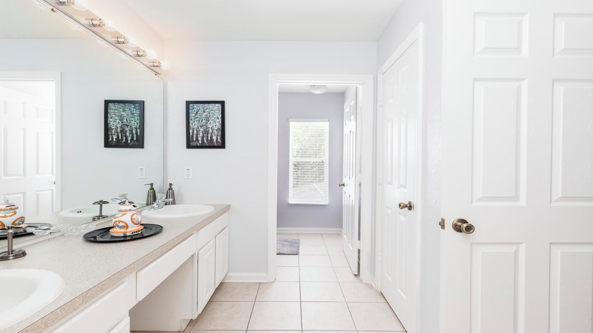 A bathroom with two sinks, a large mirror, and a Star Wars-themed decoration.