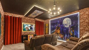 A cozy room with brick walls, leather recliners, a large screen TV, and a mural of a castle under a moonlit sky. - Bella Vida 12br Kids World With Pool Spa Near Disney 4497 (Kissimmee)