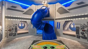 A room with a blue slide, Star Wars-themed walls, and a Star Wars-themed carpet. - Bella Vida 12br Kids World With Pool Spa Near Disney 4497 (Kissimmee)