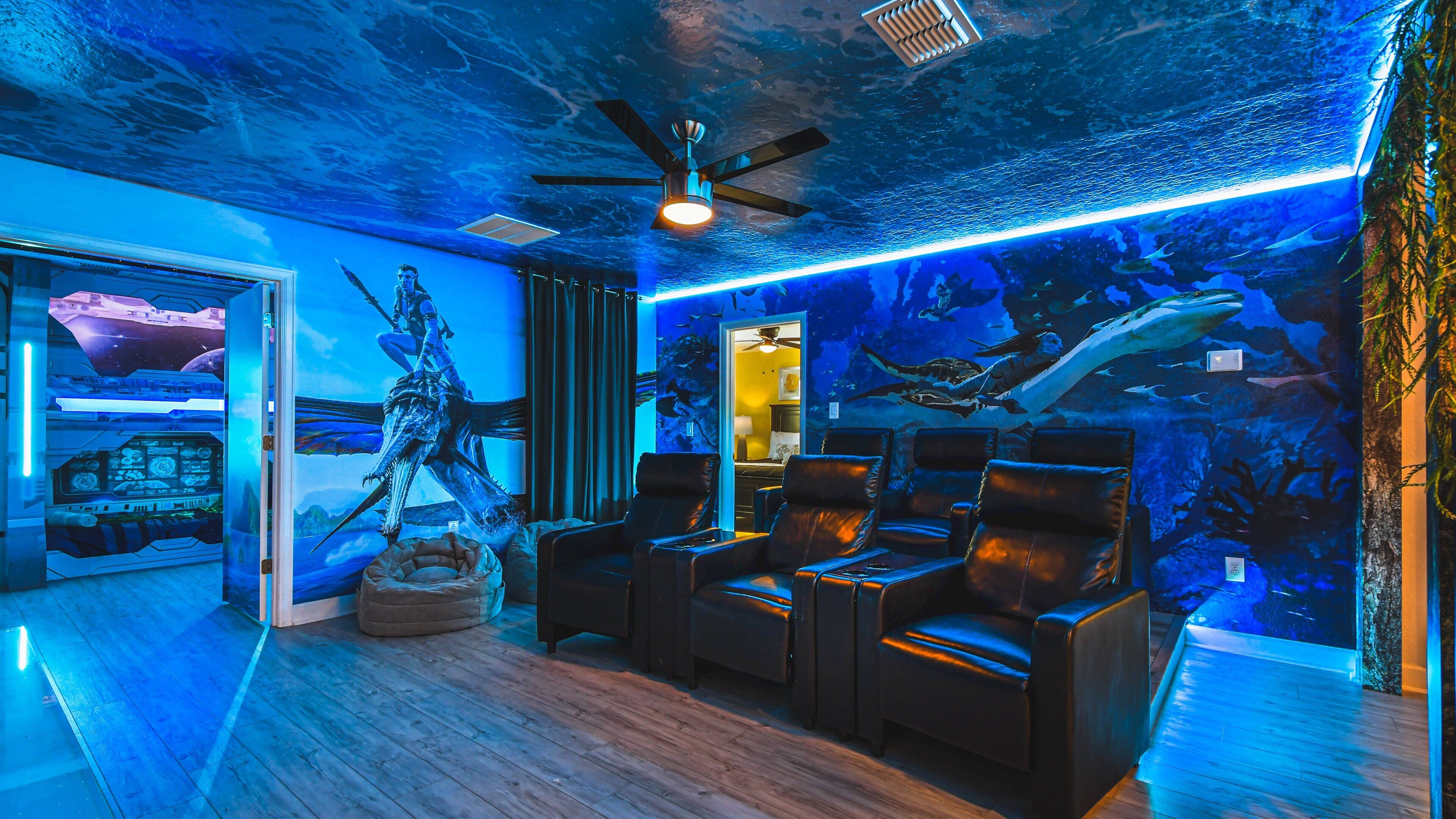 A room with a ceiling fan, a large mural of an underwater scene, and several leather chairs.