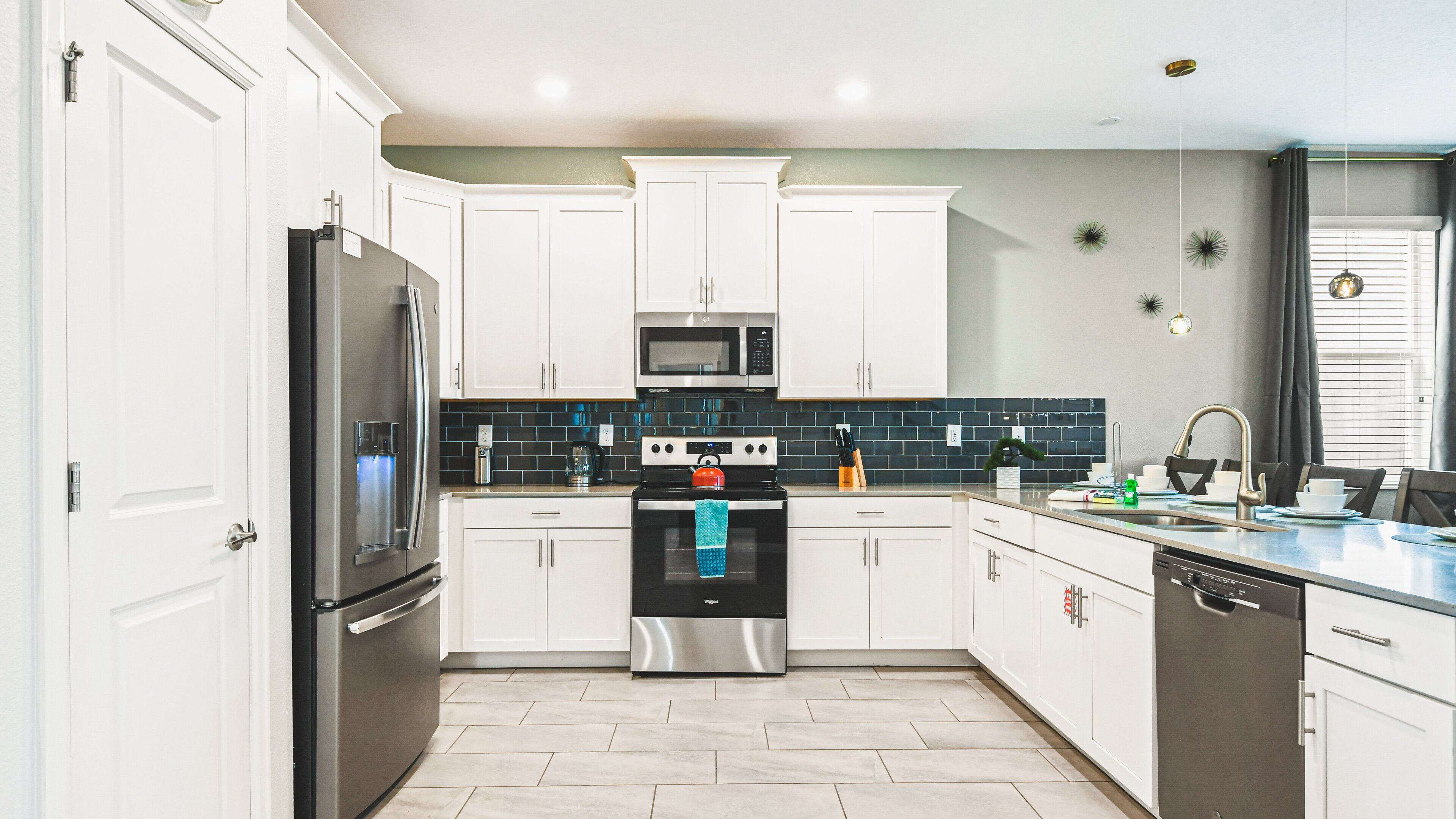 A modern kitchen with white cabinets, stainless steel appliances, and a tiled backsplash.