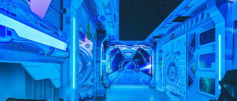 A futuristic hallway with a starry view through the windows, leading to an exit.