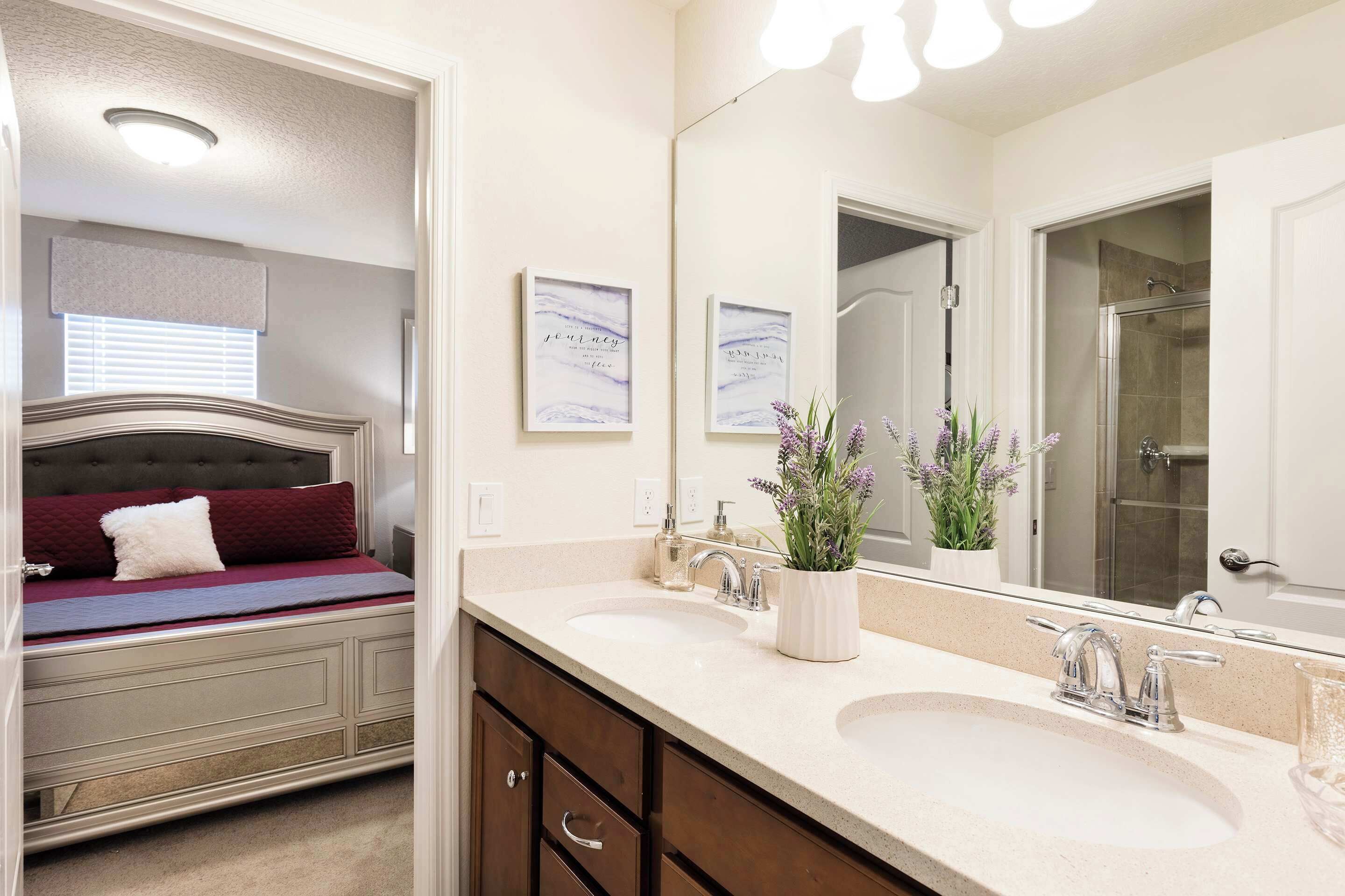 A bedroom with a bed, a bathroom with a sink and mirror, and a shower.