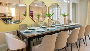A dining area with a long table set for six, surrounded by beige chairs. - Windsor At Westside Enchanting Lake 2401 (Kissimmee)