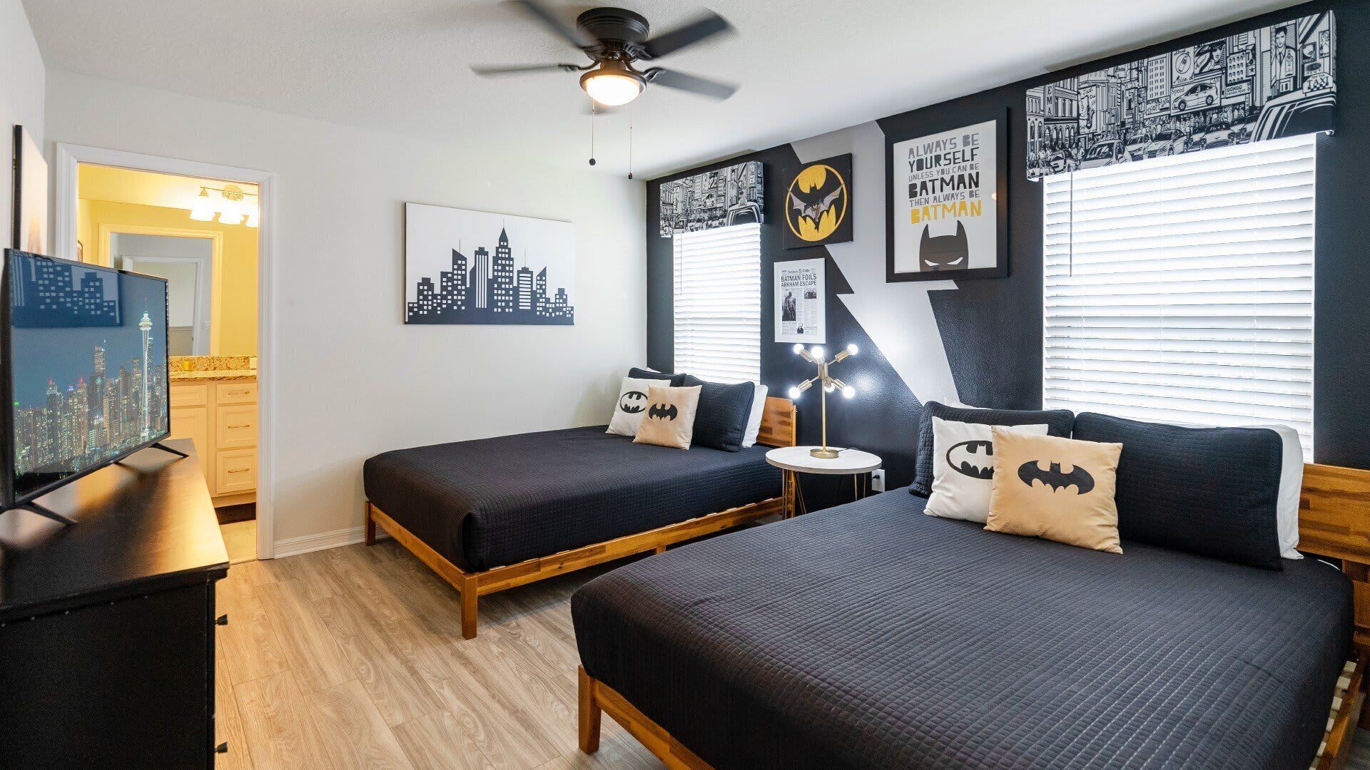 A bedroom with two beds, a ceiling fan, and a cityscape poster on the wall.