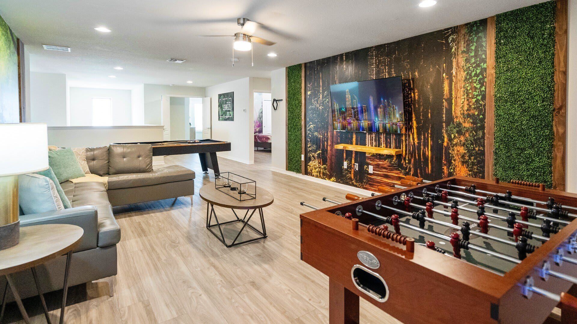 A modern living room with a foosball table, a pool table, and a sofa.