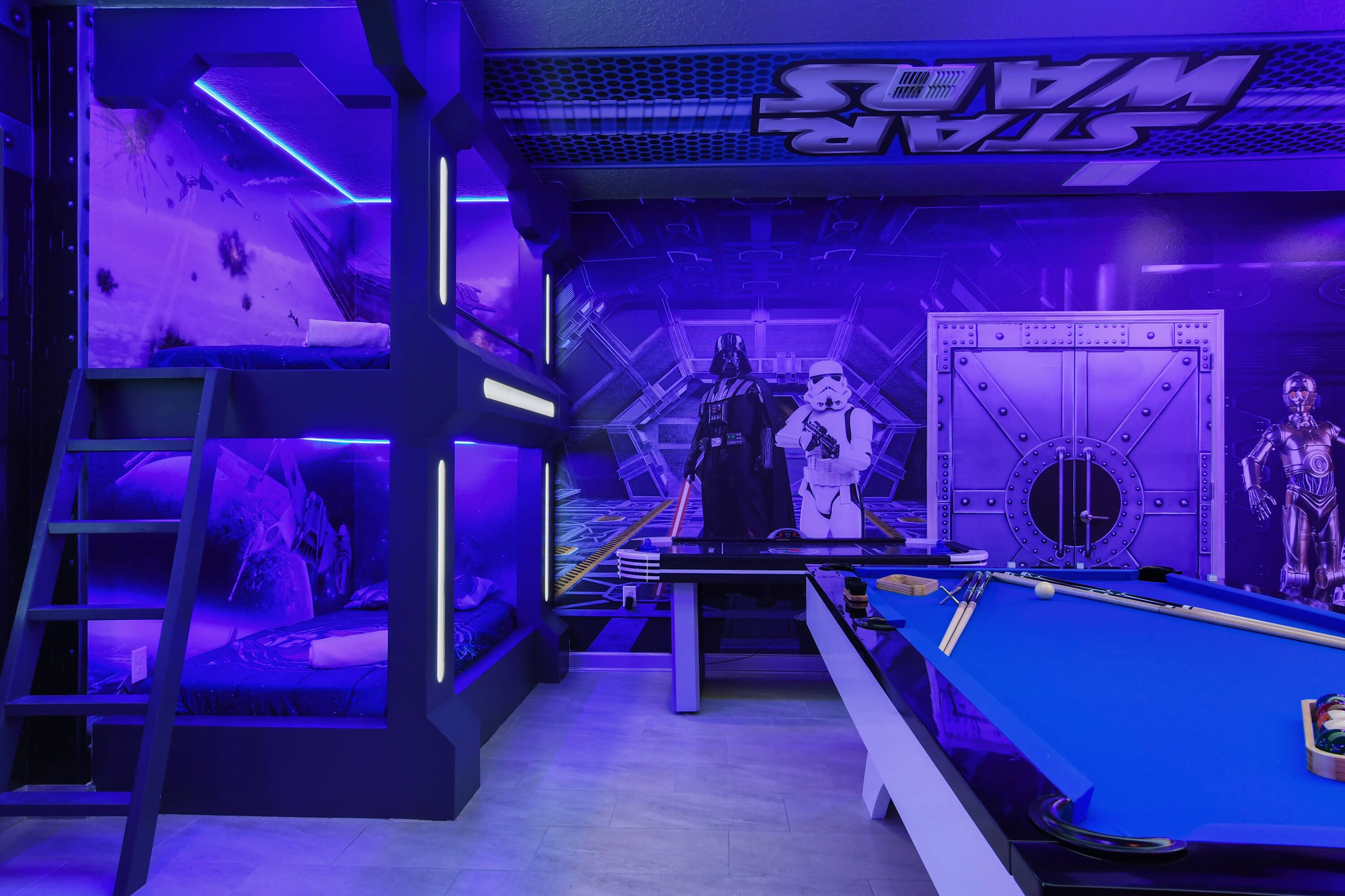 Una stanza a tema Star Wars con tavolo da biliardo, scaletta e oggetti da collezione di Star Wars.