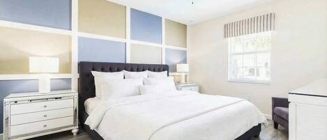 A bedroom with a bed, nightstands, a desk, a ceiling fan, and a window.