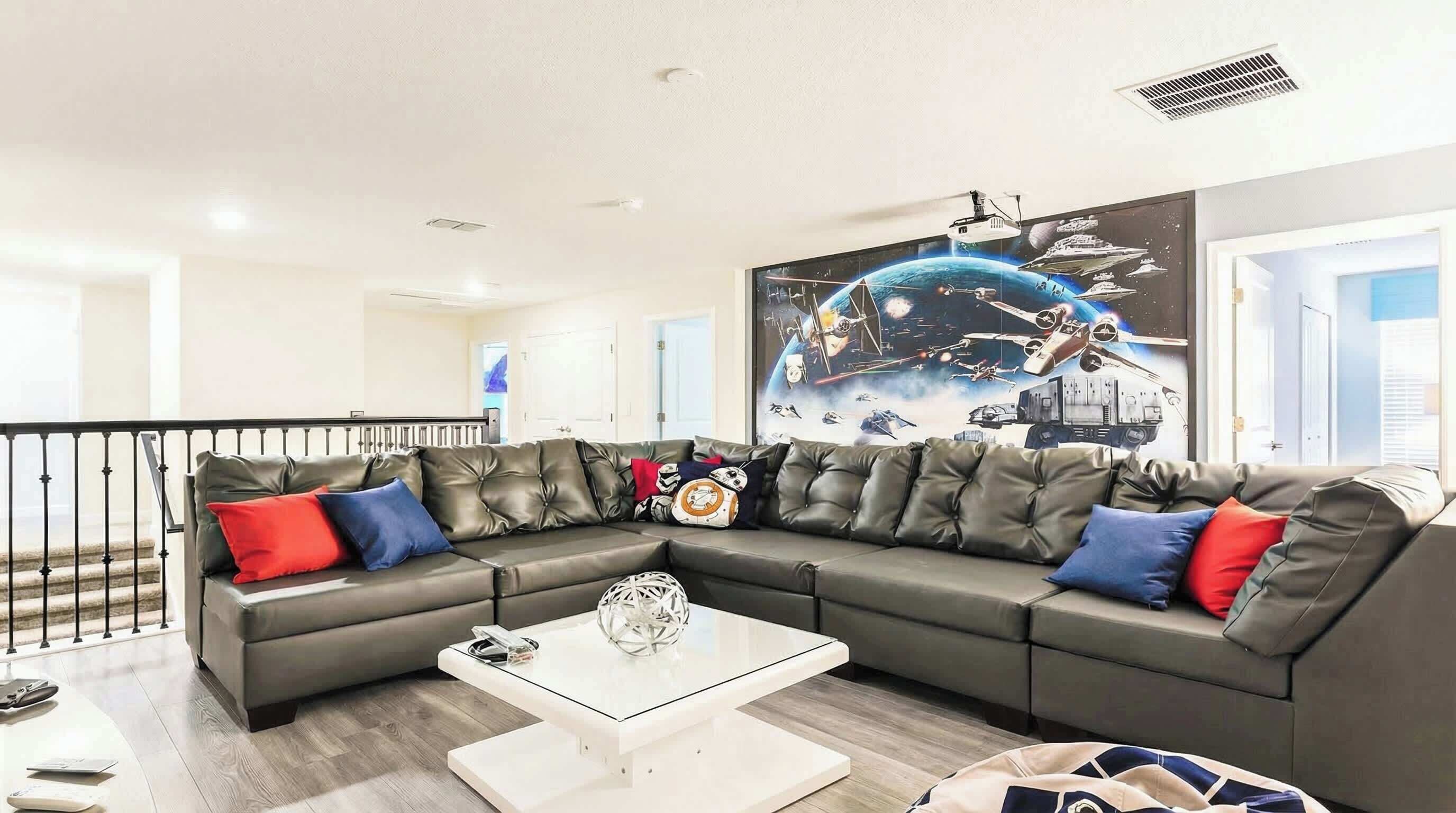A modern living room with a sectional sofa, a coffee table, and a large space-themed mural on the wall.
