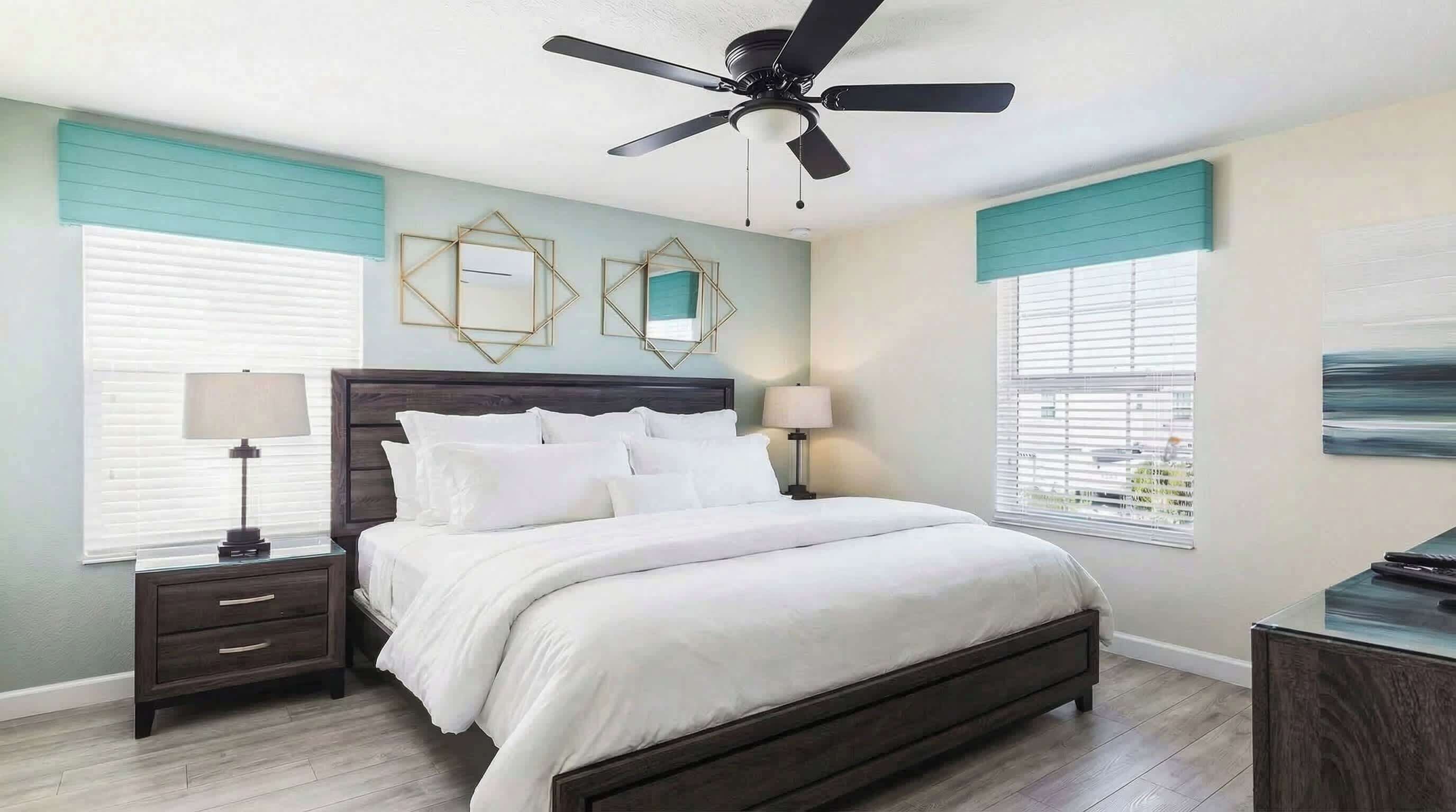 A bedroom with a bed, nightstands, a ceiling fan, and two wall-mounted mirrors.