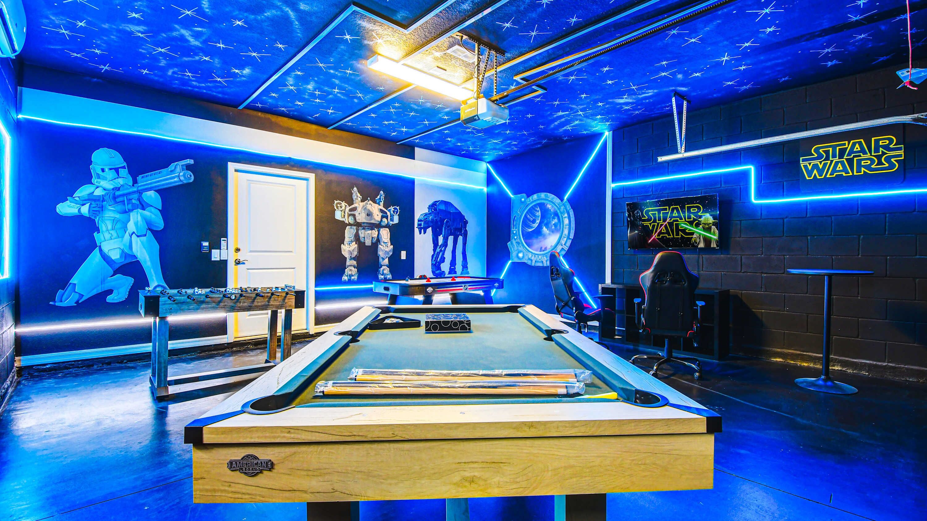 A pool table in a room with Star Wars-themed decorations, including a neon sign and wall art.