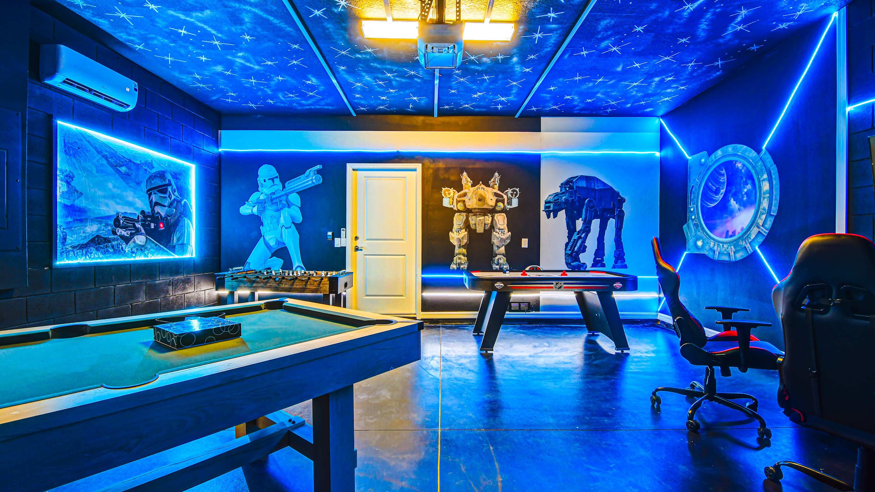 A gaming room with a pool table, a foosball table, and Star Wars-themed decorations.