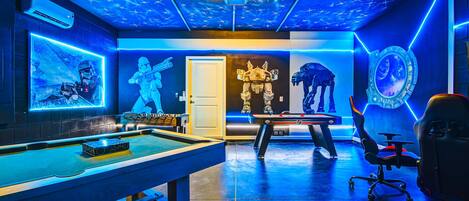 A gaming room with a pool table, a foosball table, and Star Wars-themed decorations.
