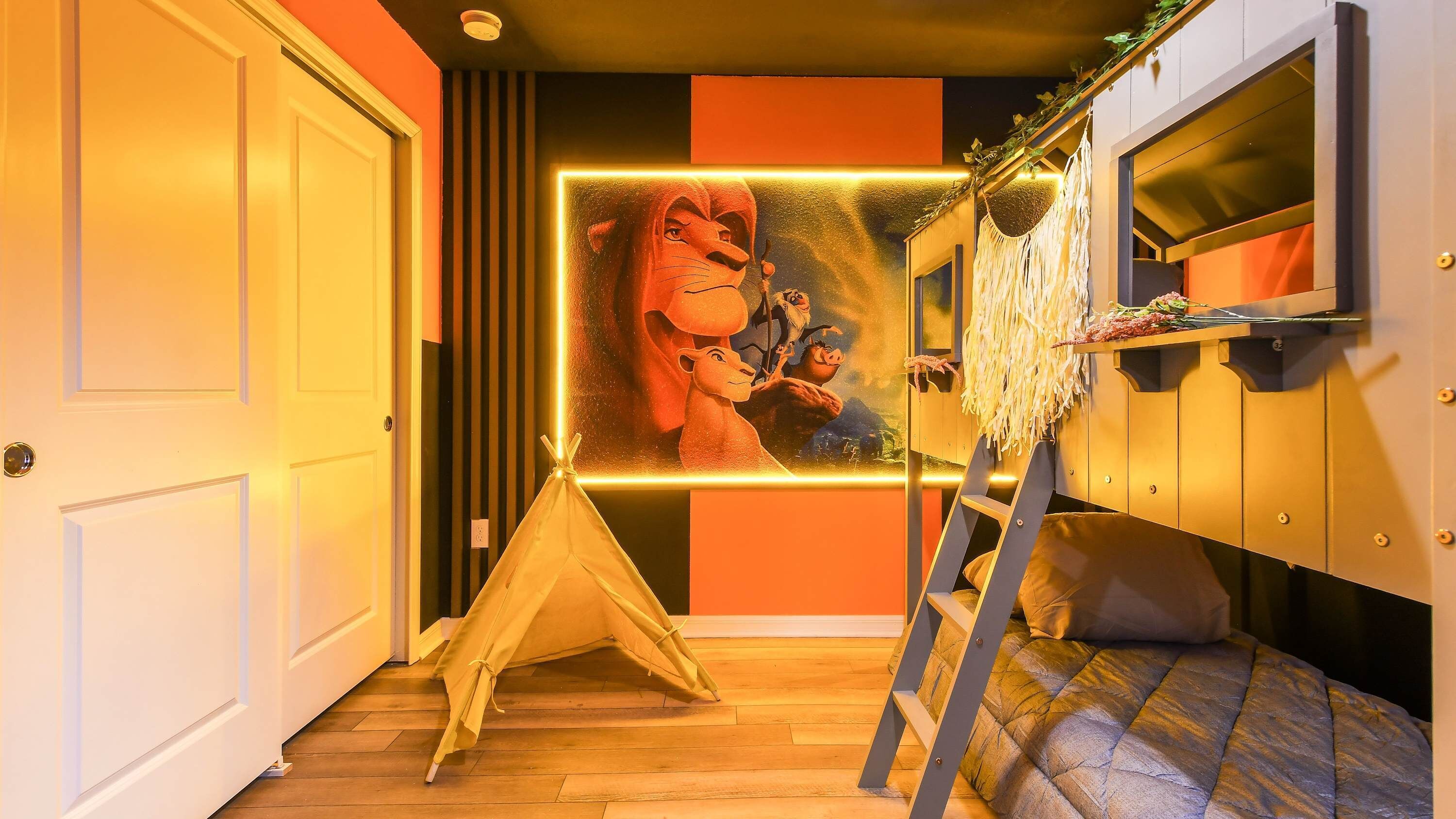 A room with a bed, a ladder, a tent, and a wall with a framed picture.
