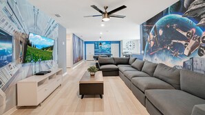 A modern living room with a large gray sectional sofa, a white entertainment unit, and a ceiling fan. - Windsor Island Let's Make Sunny Memories 2316 (Davenport)