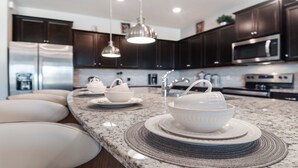 A modern kitchen with dark cabinets, stainless steel appliances, and a granite countertop. - Windsor Island Let's Make Sunny Memories 2316 (Davenport)