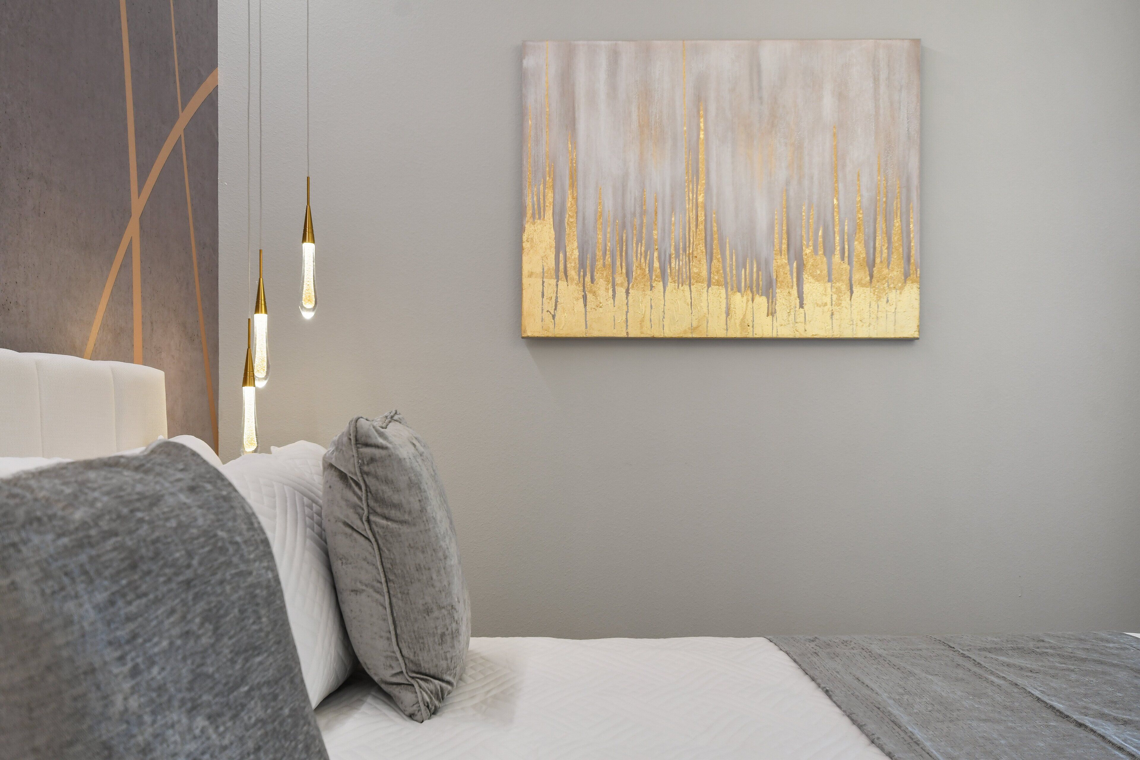 A modern bedroom with a large bed, a gray headboard, and a minimalist painting on the wall.