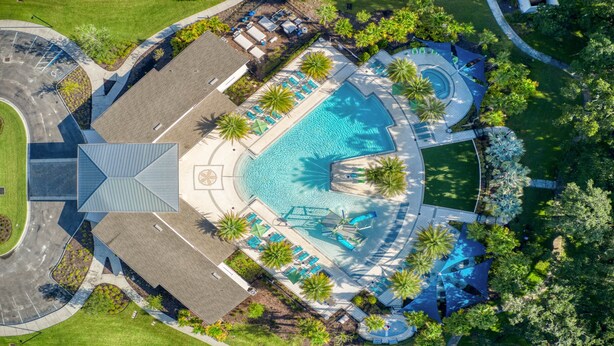 Luchtbeeld van een resort met een centraal zwembad, omgeven door palmbomen en ligbedden.