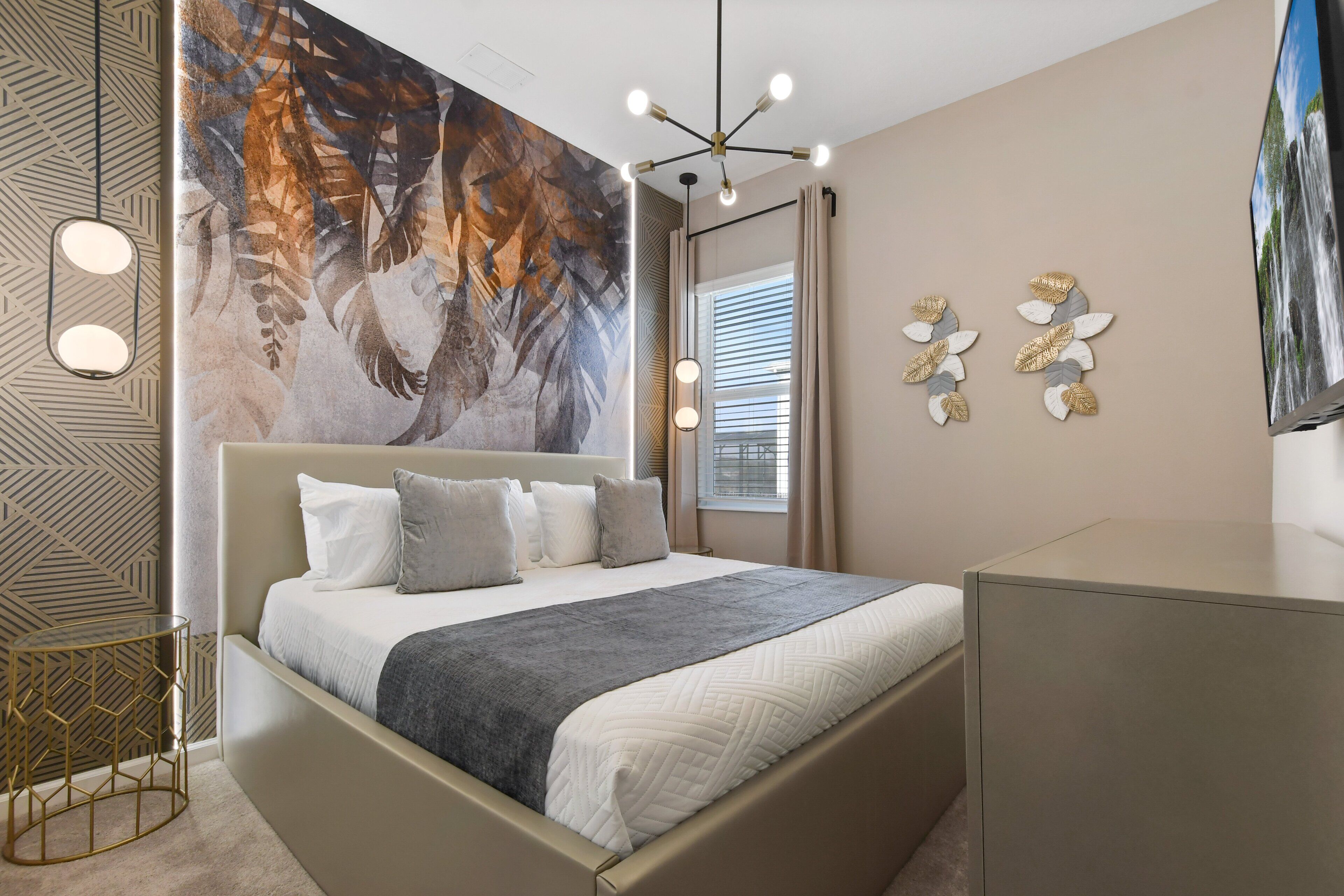 A modern bedroom with a bed, a large abstract mural, a TV, and a unique geometric side table.