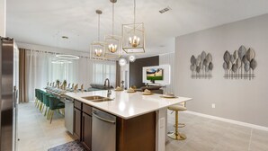 Een moderne keuken met een centraal eiland, roestvrijstalen apparatuur en hanglampen.