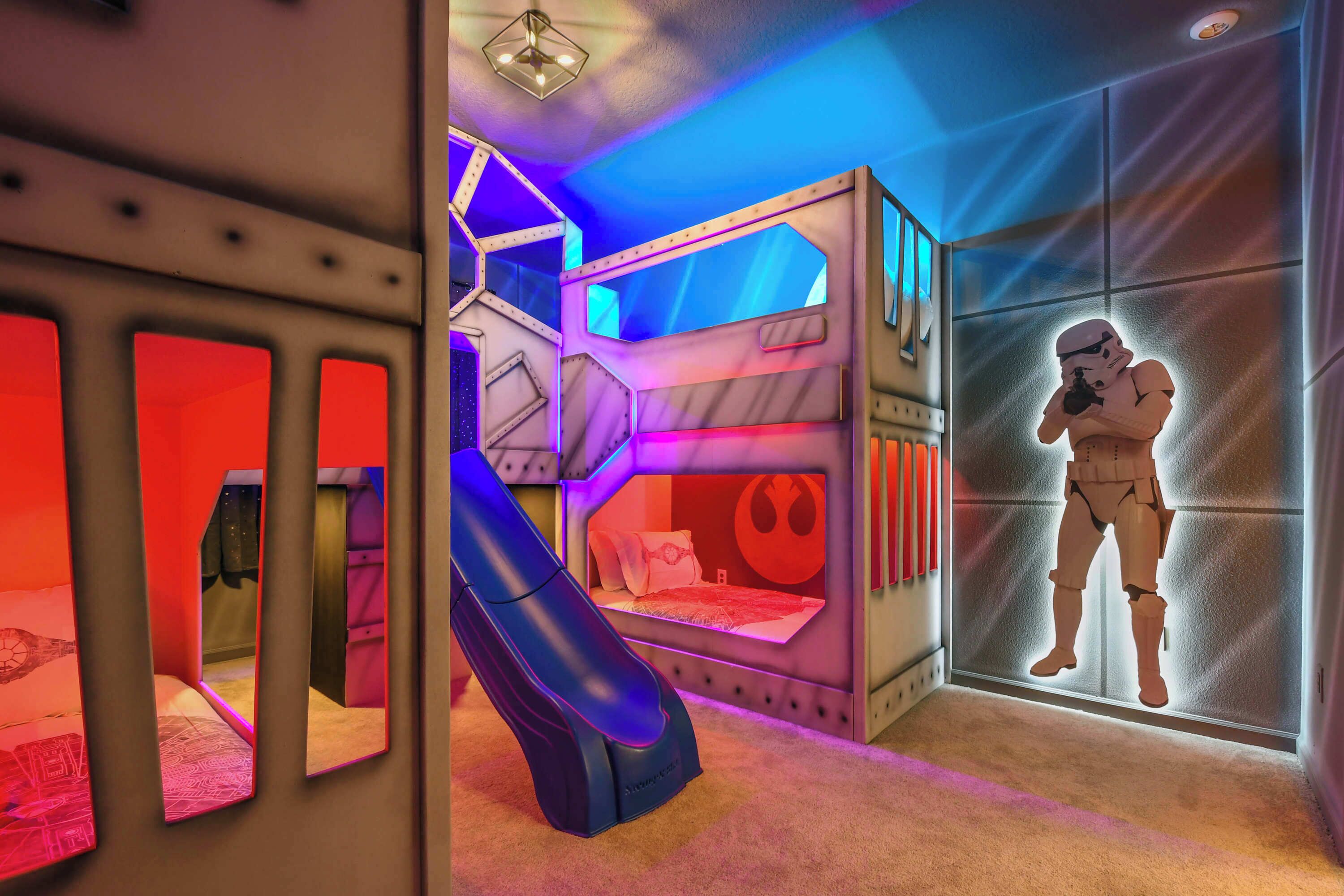 A room with a bunk bed, a slide, and a Star Wars-themed decoration.