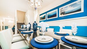 Un comedor con una larga mesa dispuesta para varios comensales, con individuales azules y servilletas blancas.