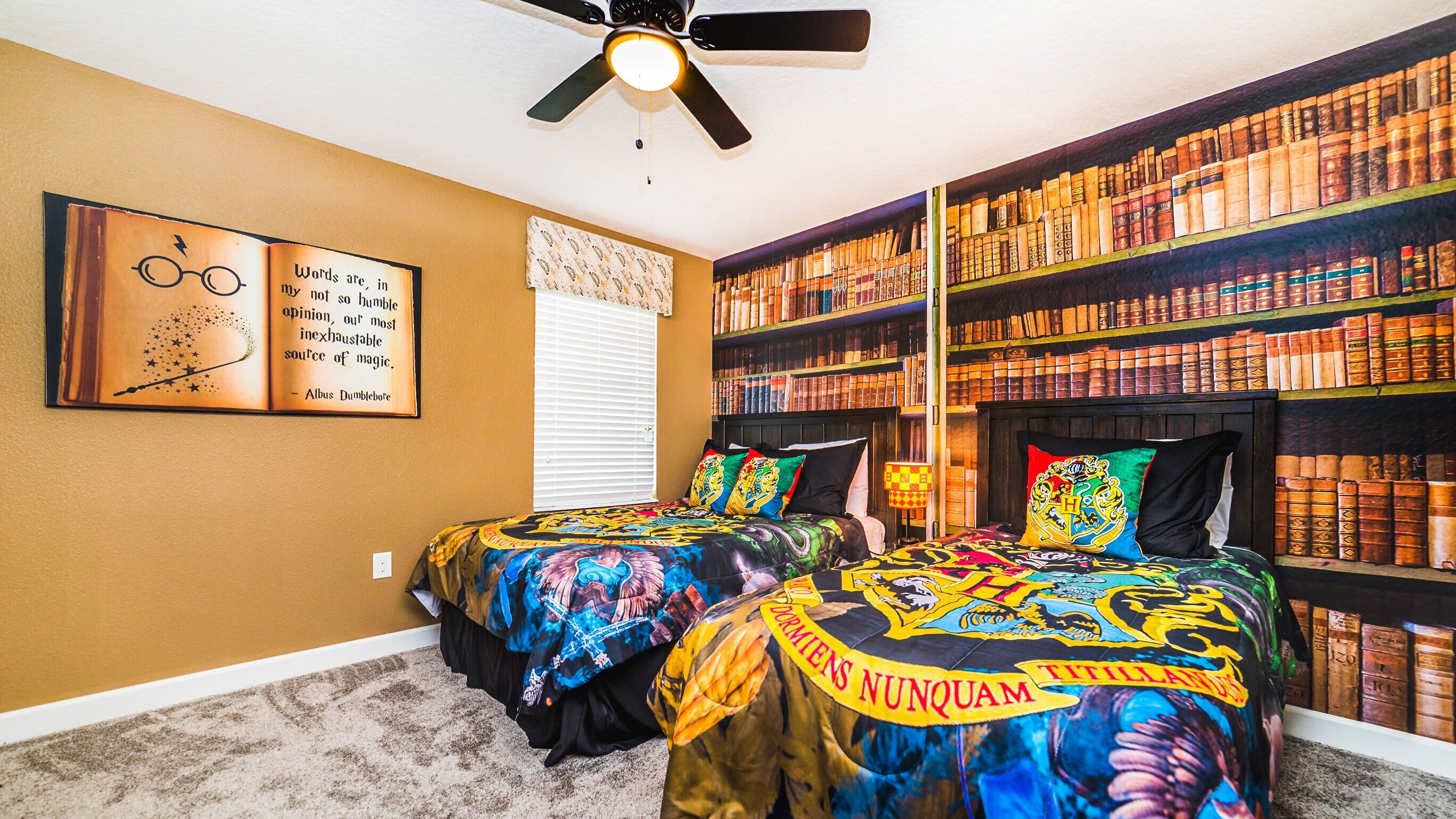A bedroom with two beds, a ceiling fan, and a bookshelf filled with books.