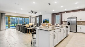 A modern kitchen with a large island, white cabinetry, and stainless steel appliances. - Resort-style Home With Pool, Near Disney! (Kissimmee)