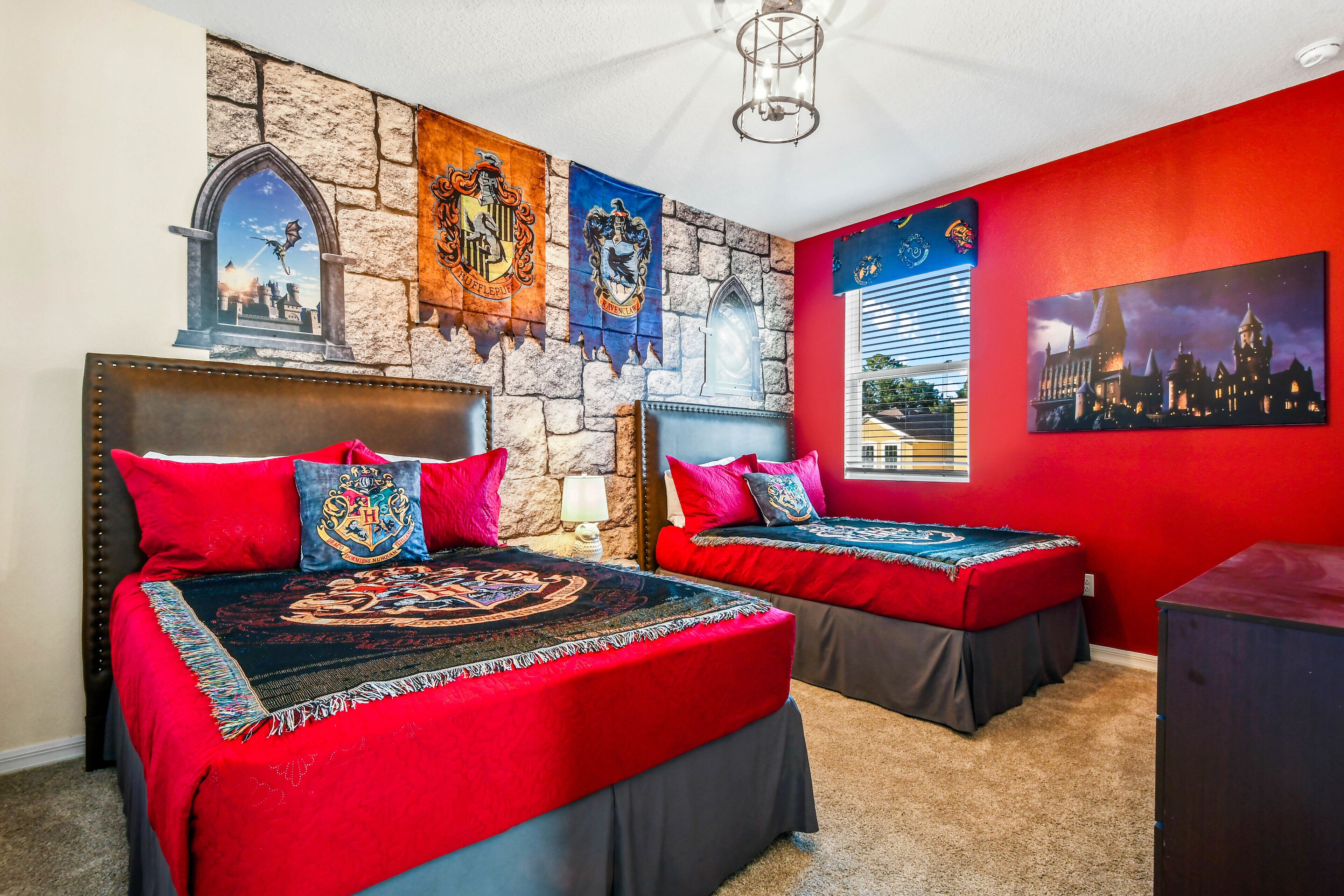 A bedroom with two beds, red walls, stone wall accents, and a cityscape painting.
