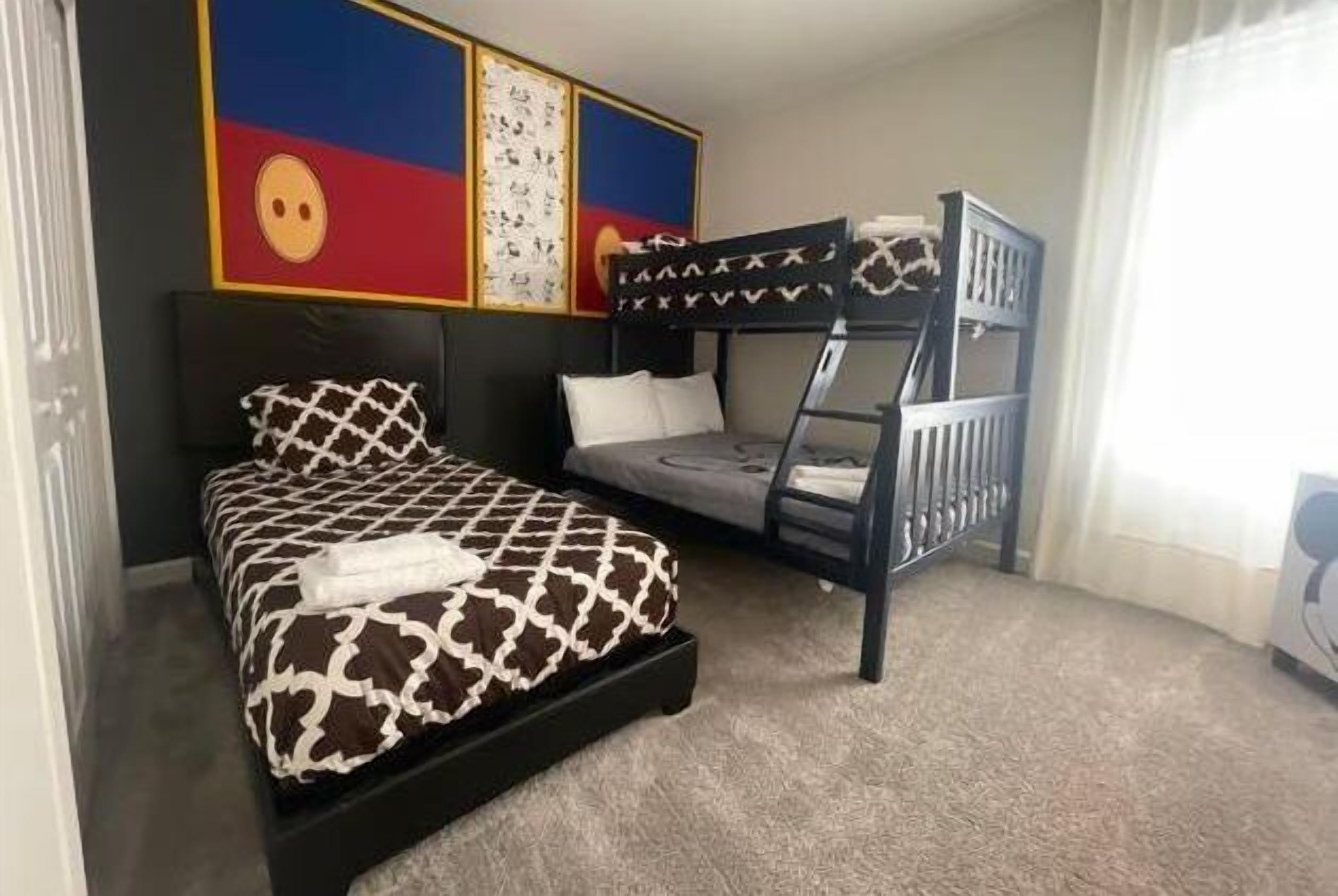 Une chambre avec un lit, un lit superposé et un mur décoré d’œuvres d’art.