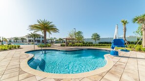 A swimming pool with a circular design, surrounded by palm trees and lounge chairs.