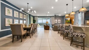 A modern dining area with a long table, multiple chairs, and a ceiling fan. - Comfort & Luxury Near Orlando Attractions (Davenport)