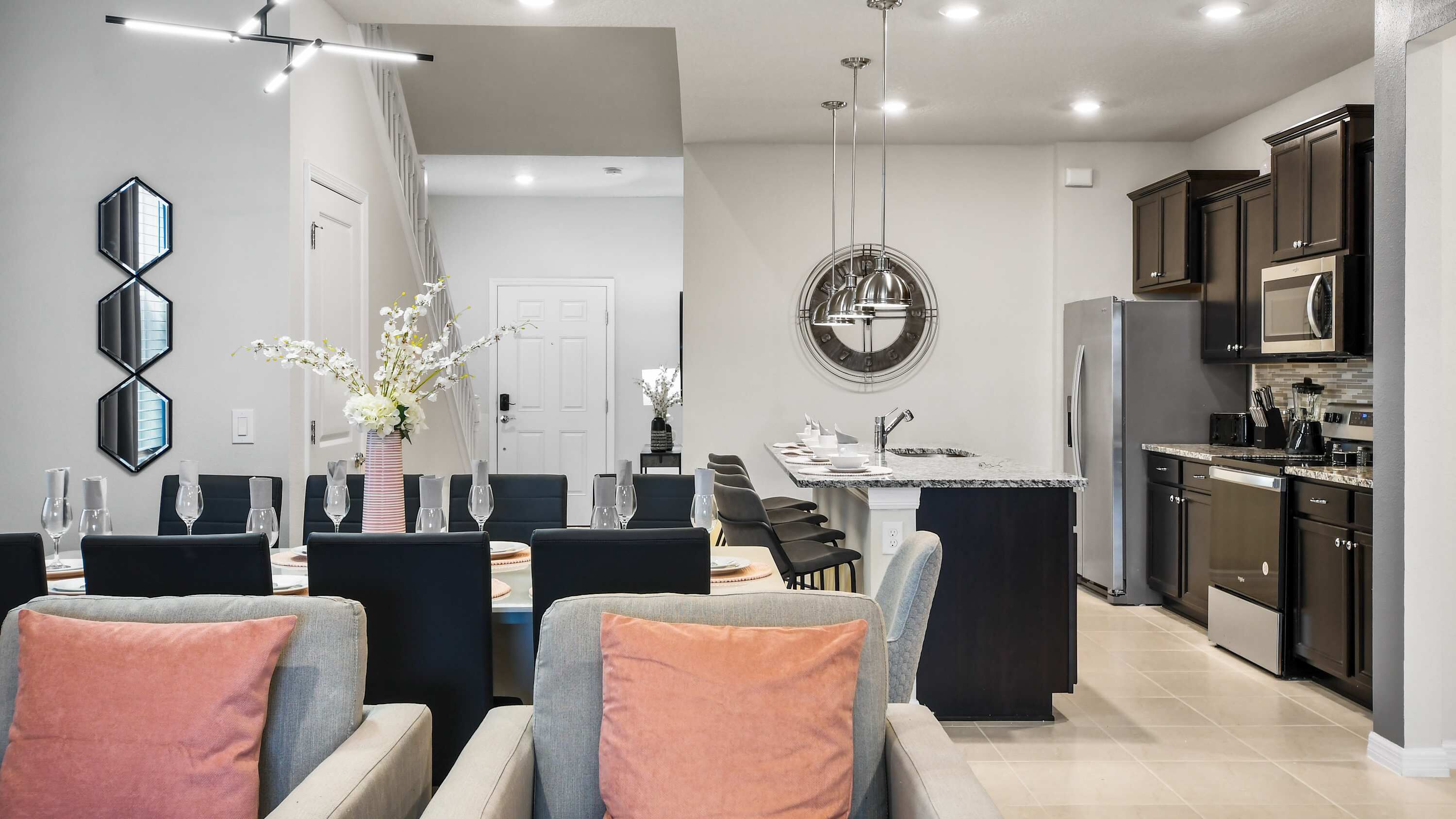 A modern kitchen with dark cabinets, a built-in microwave, and a stainless steel refrigerator.