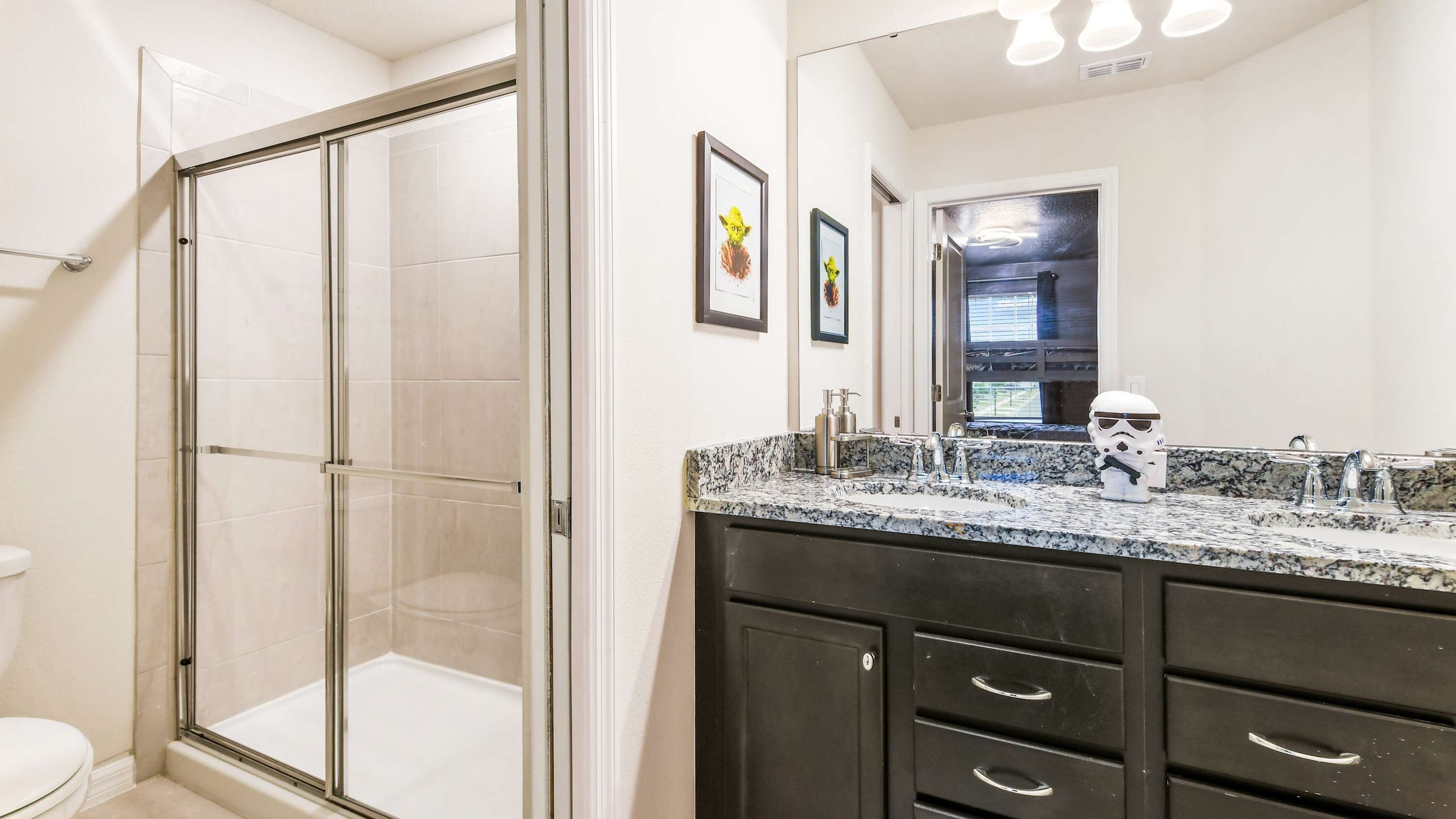 Une salle de bain moderne avec une douche à parois de verre, un lavabo en marbre et un meuble-lavabo foncé doté de tiroirs.