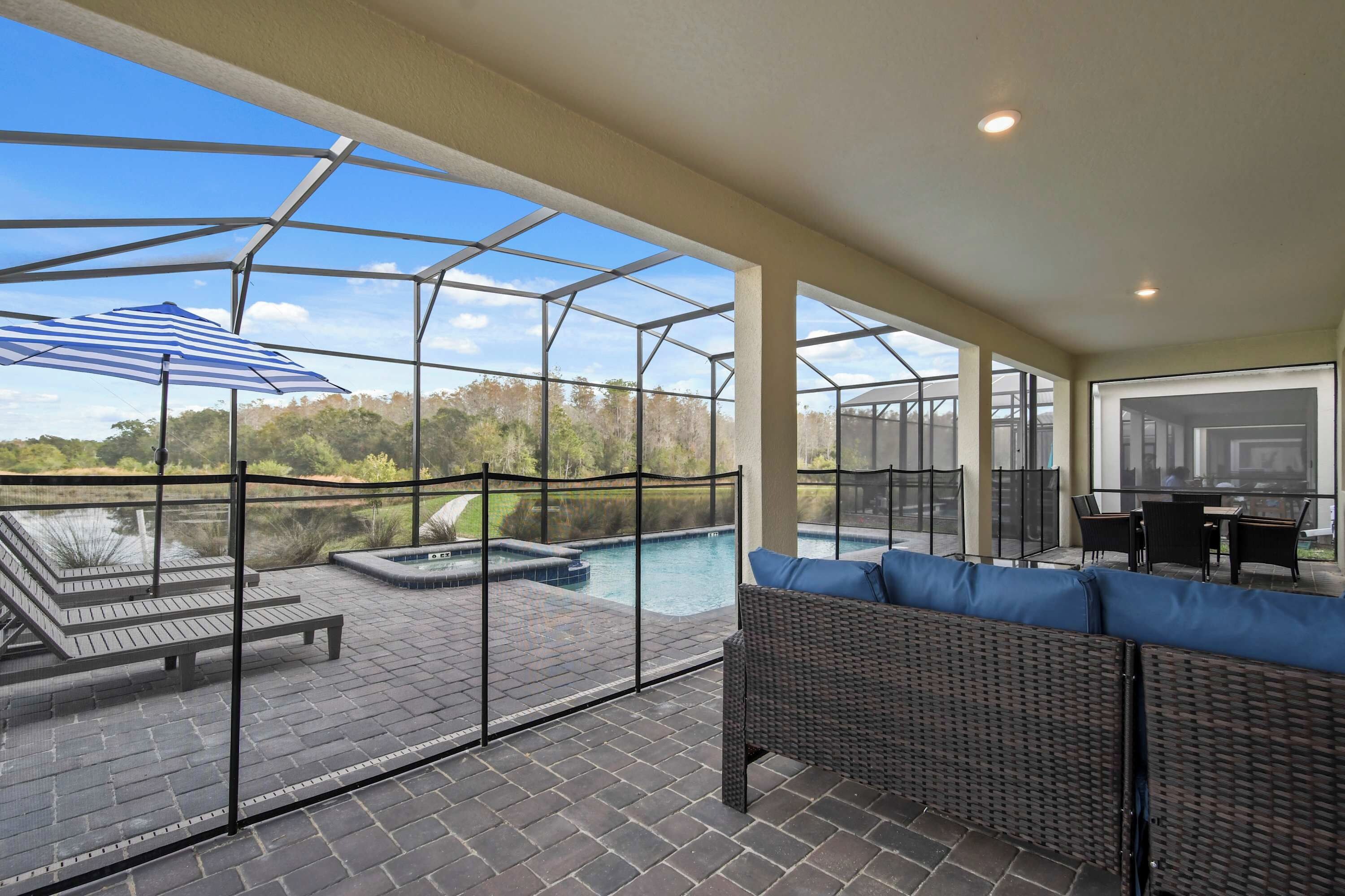 A covered outdoor area with a pool, seating, and a view of the surrounding landscape.