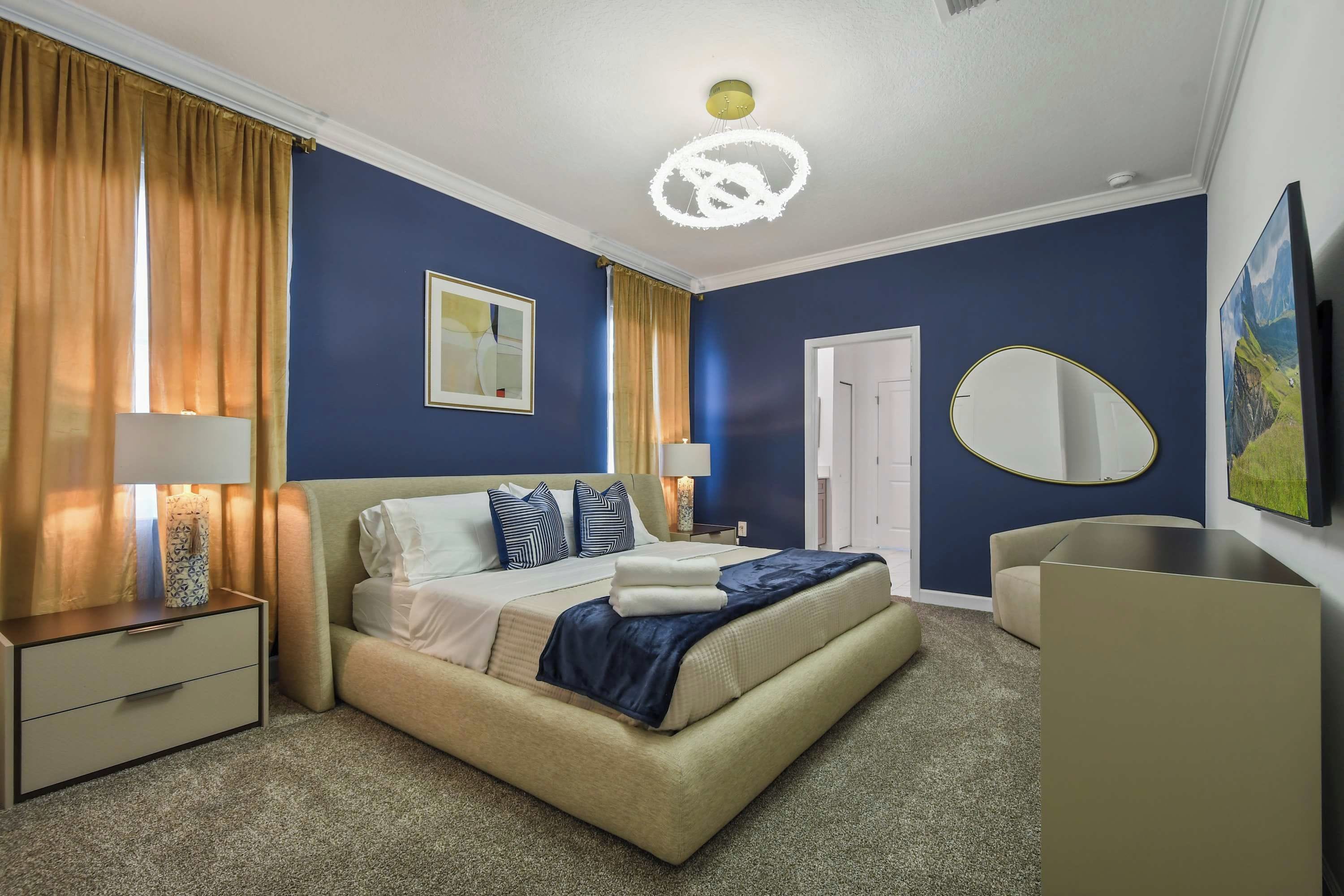 Een hotelkamer met een bed, nachtkastjes, een spiegel, een televisie en een deur.