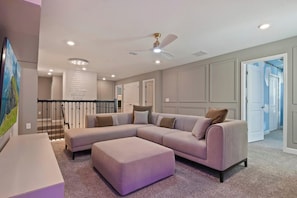 A modern living room with a sectional sofa, a small ottoman, a ceiling fan, recessed lighting, and a staircase leading to another level. - Storey Lake Fantastic Star Wars Villa With Lakeview 2913 (Kissimmee)