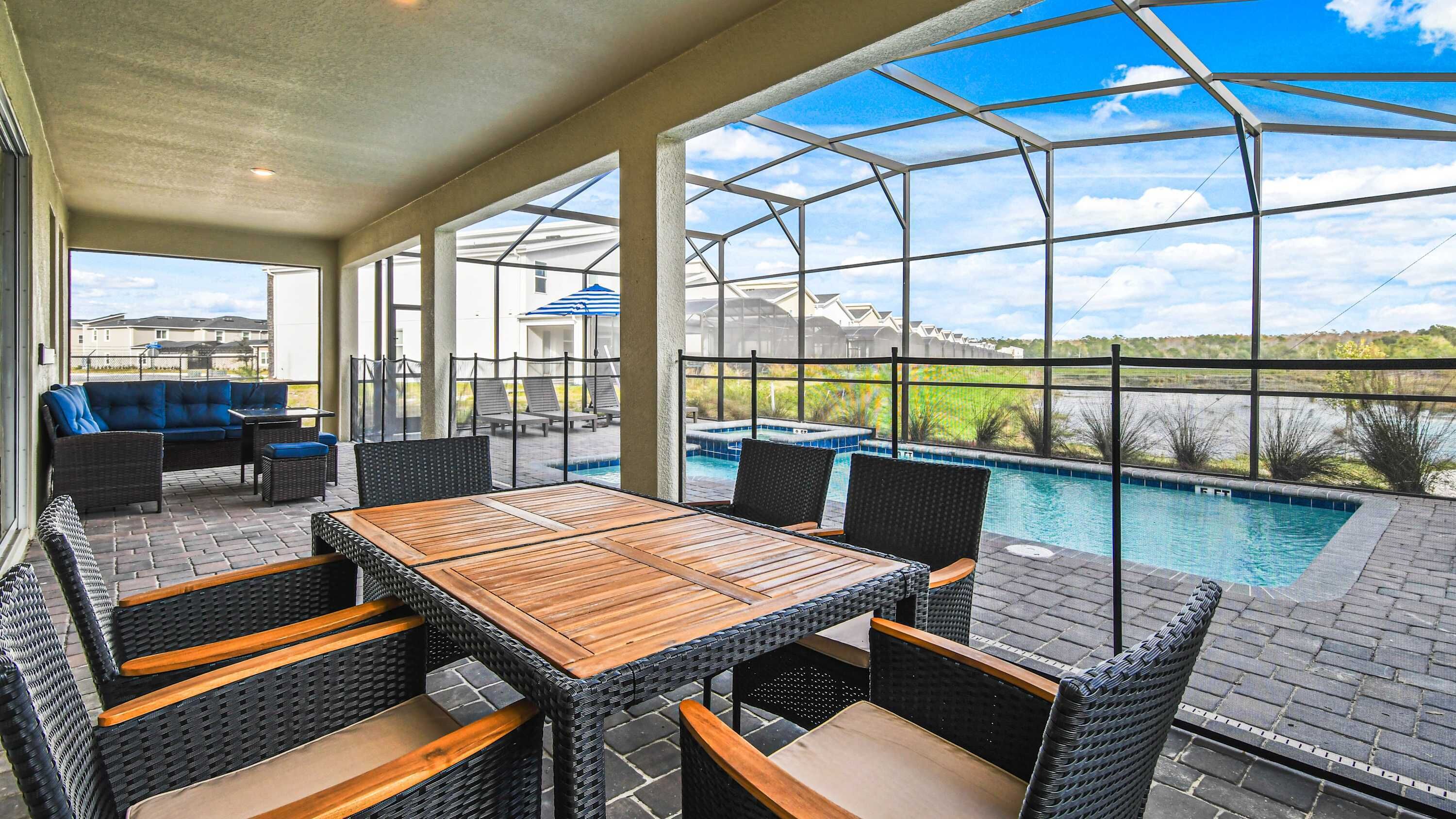 A covered outdoor area with a pool, wicker furniture, and a view of the landscape.