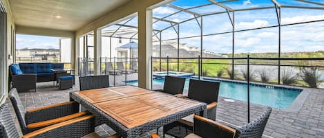 A covered outdoor area with a pool, wicker furniture, and a view of the landscape.