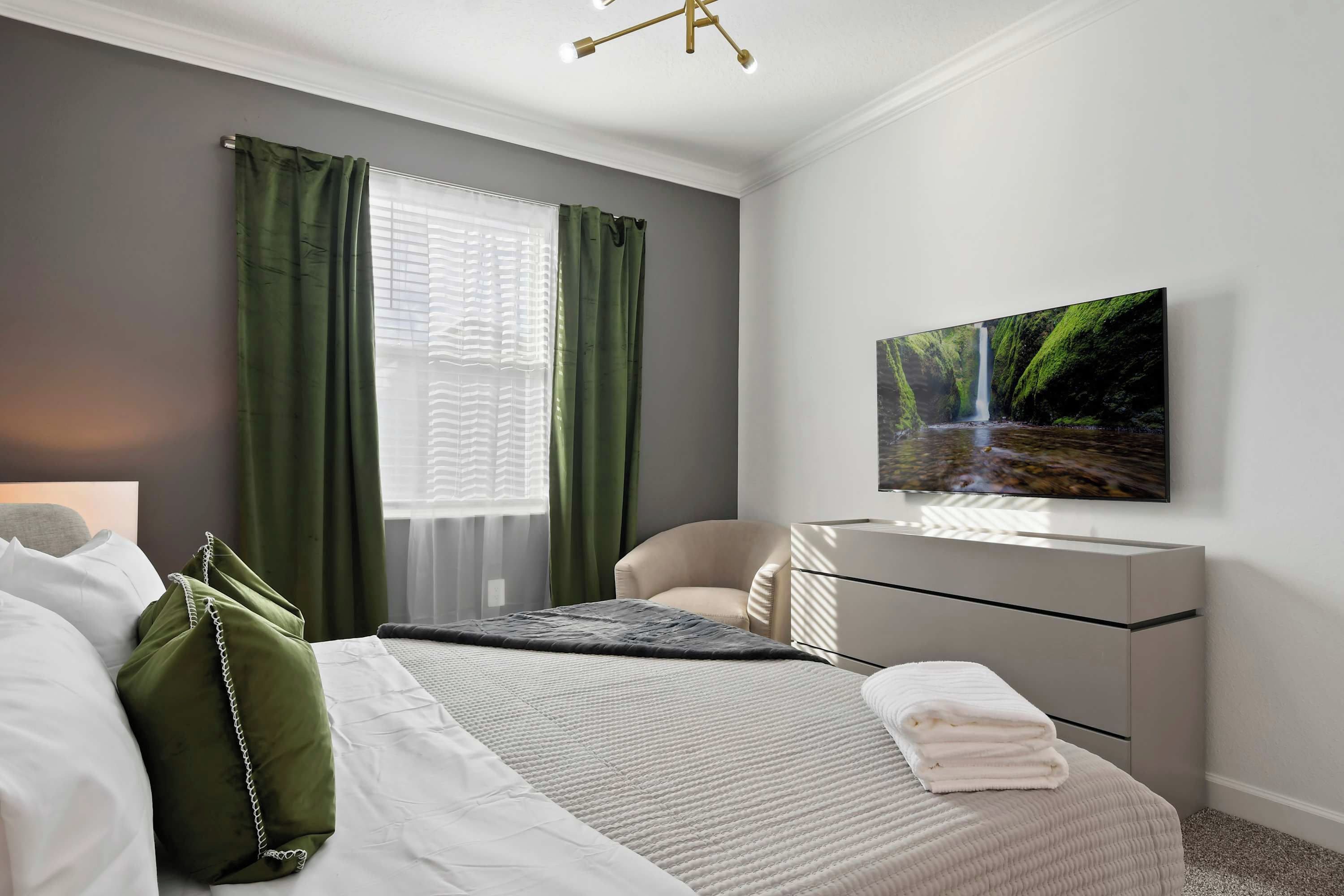 Een moderne slaapkamer met een bed, een bureau, een stoel en een schilderij aan de muur.