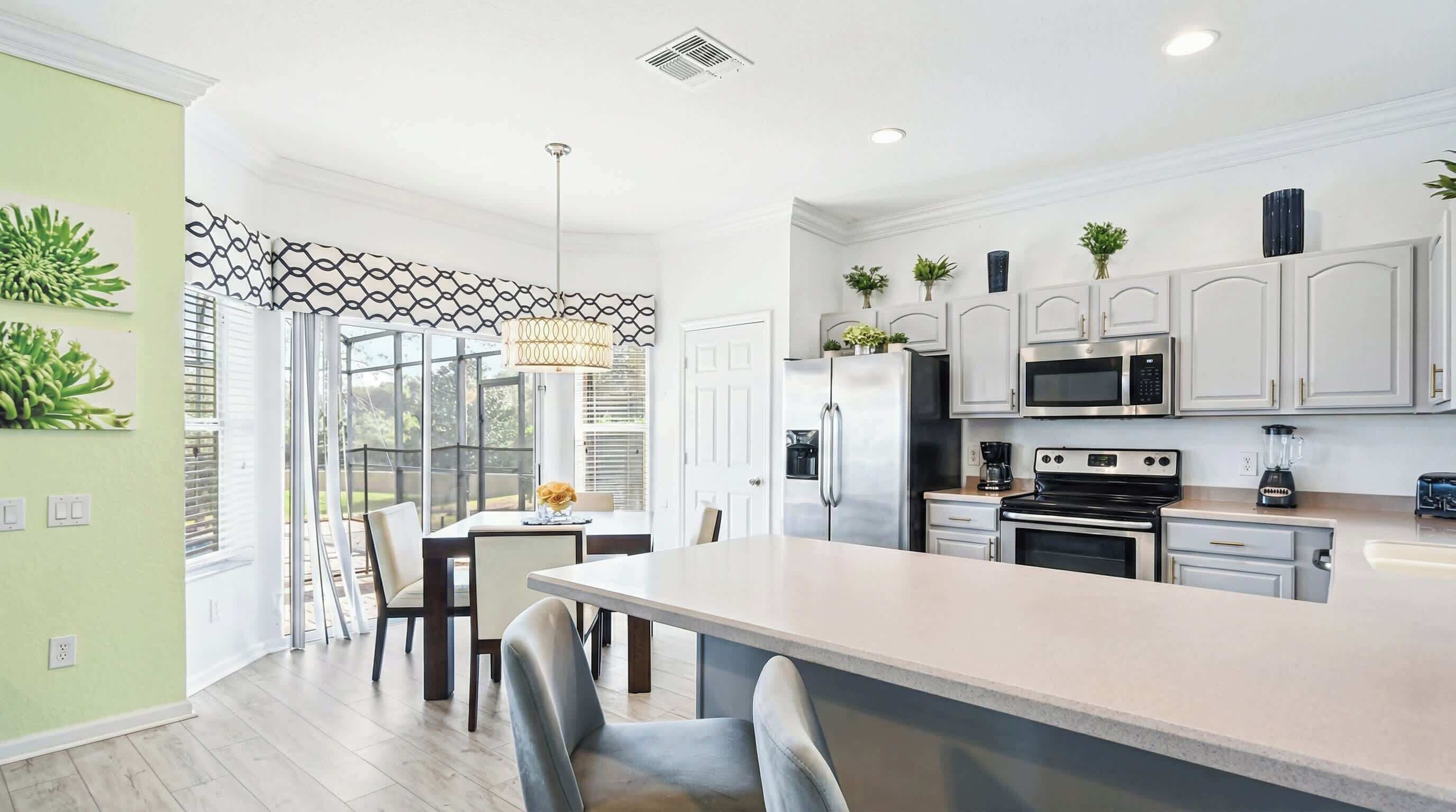 A modern kitchen with white cabinets, stainless steel appliances, and a large island.