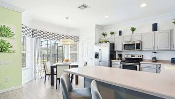A modern kitchen with white cabinets, stainless steel appliances, and a large island.
