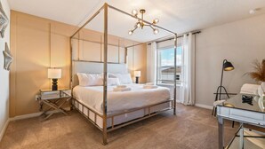 A four-poster bed with a canopy, bedside lamps, a desk with a lamp, and a view of the outside through the window. - 5BR Windsor Island Resort w Private Pool Disney (Davenport)