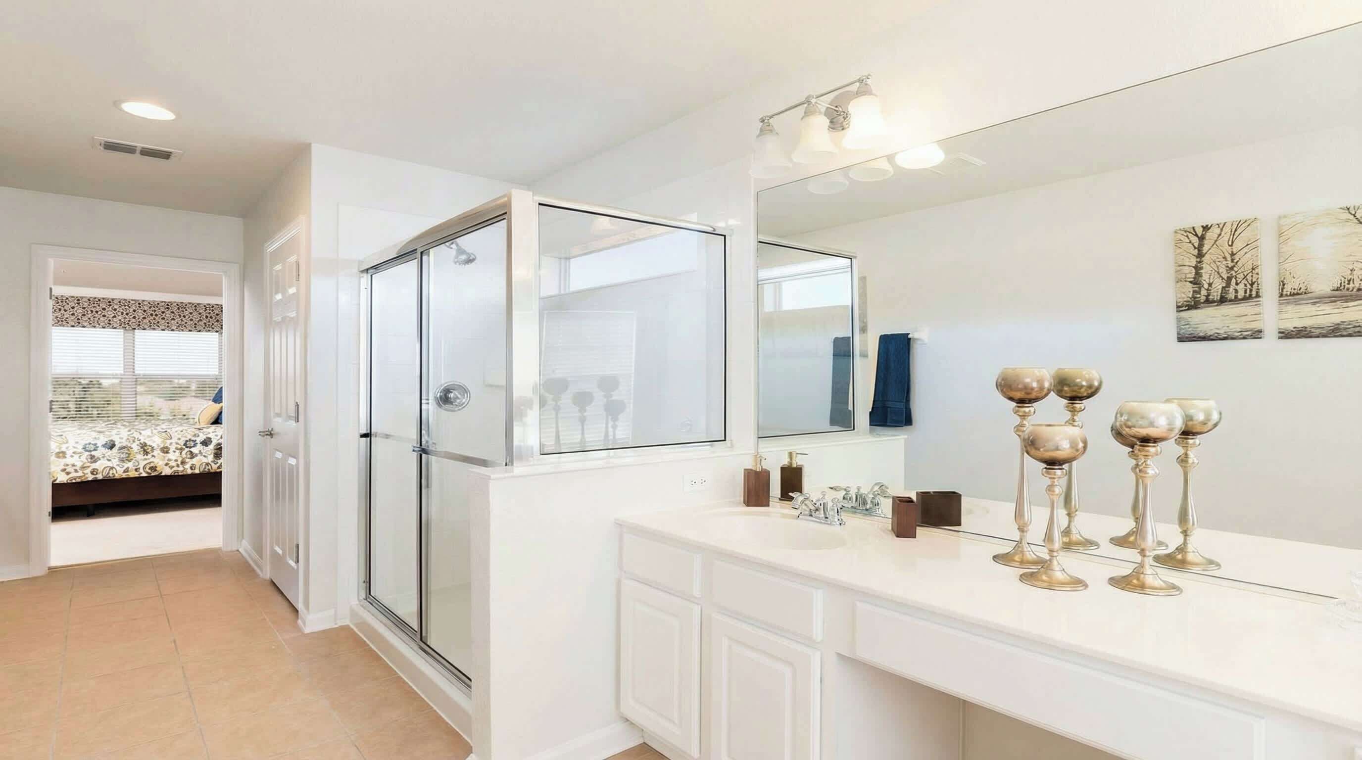 Een moderne badkamer met een glazen douchecabine, een grote spiegel en een wastafelmeubel met een wit aanrecht.