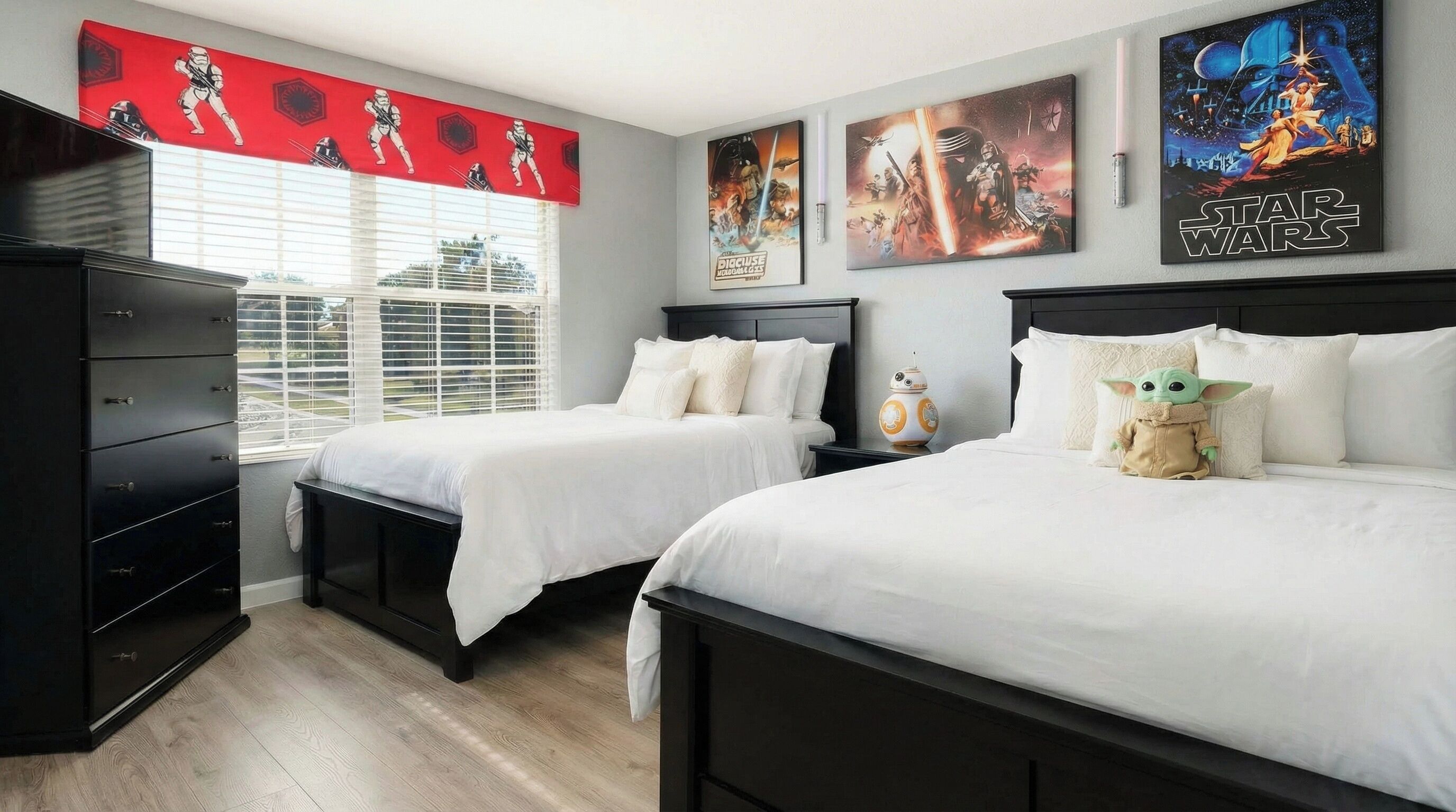 Une chambre avec deux lits, une armoire et des décorations sur le thème de Star Wars.