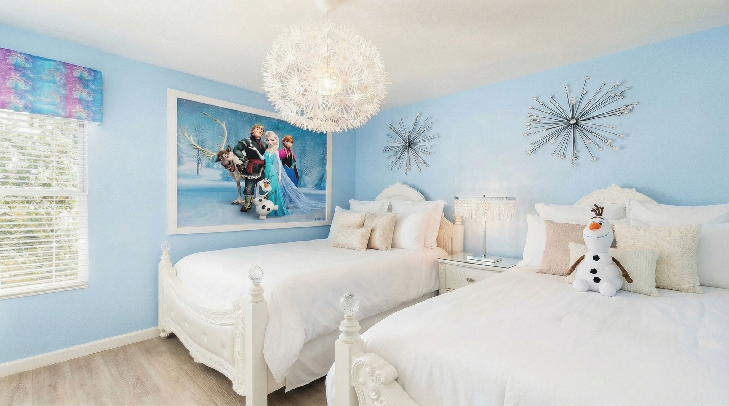 Un dormitorio con dos camas, una araña y una pared decorada con un cuadro y motivos de copos de nieve.