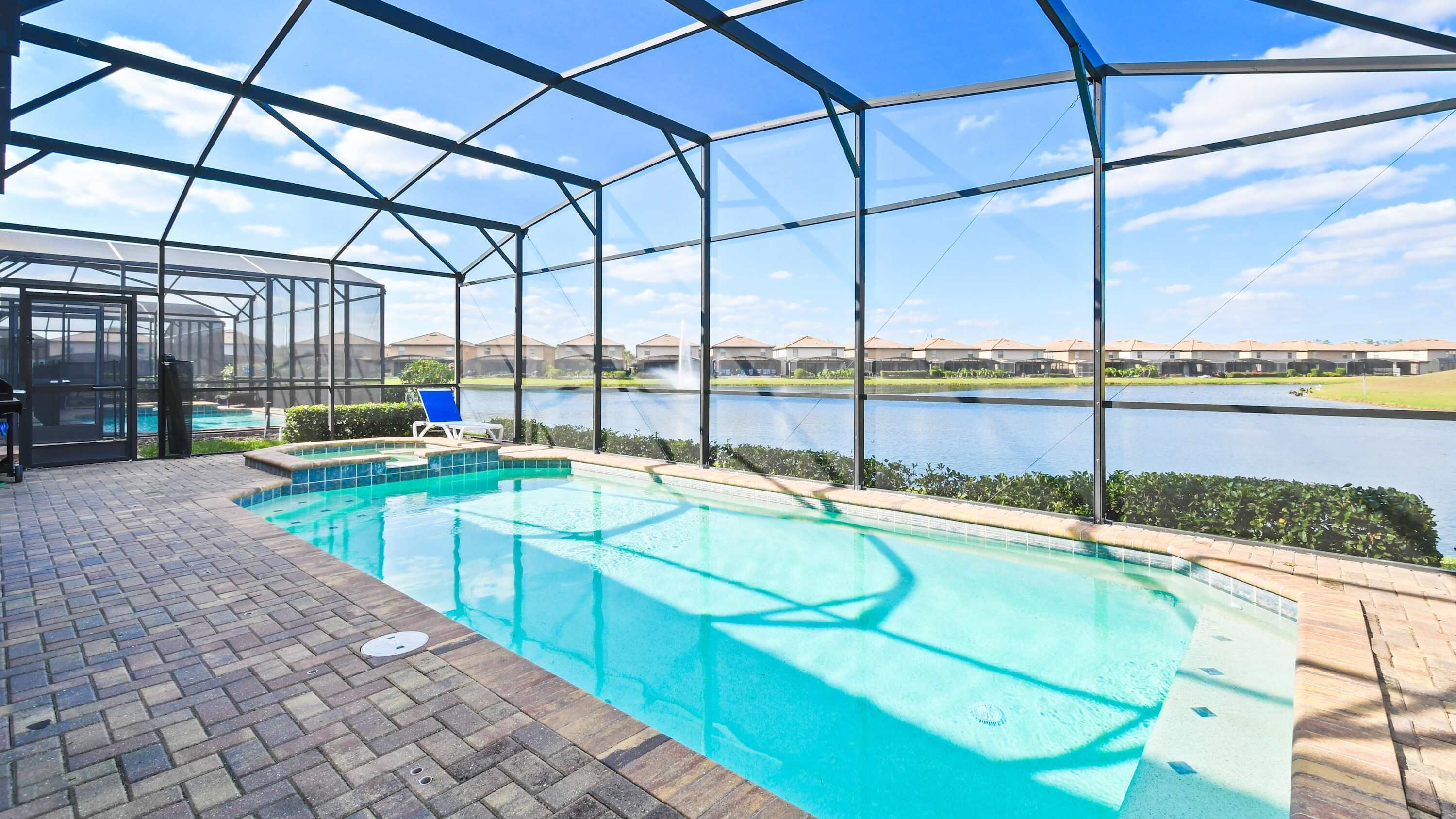 A covered outdoor swimming pool with a view of a lake and buildings in the background.