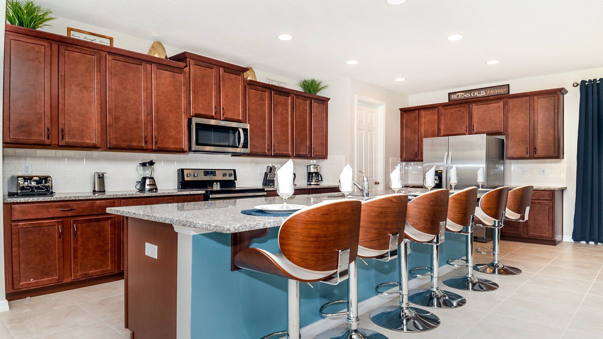 A modern kitchen with wooden cabinets, stainless steel appliances, and a bar area with bar stools.